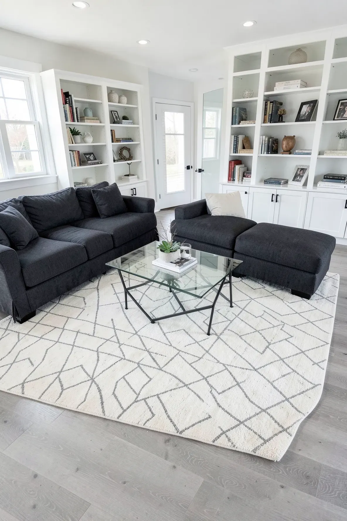 A modern living room with a cream and grey diamond patterned rug under a glass coffee table.