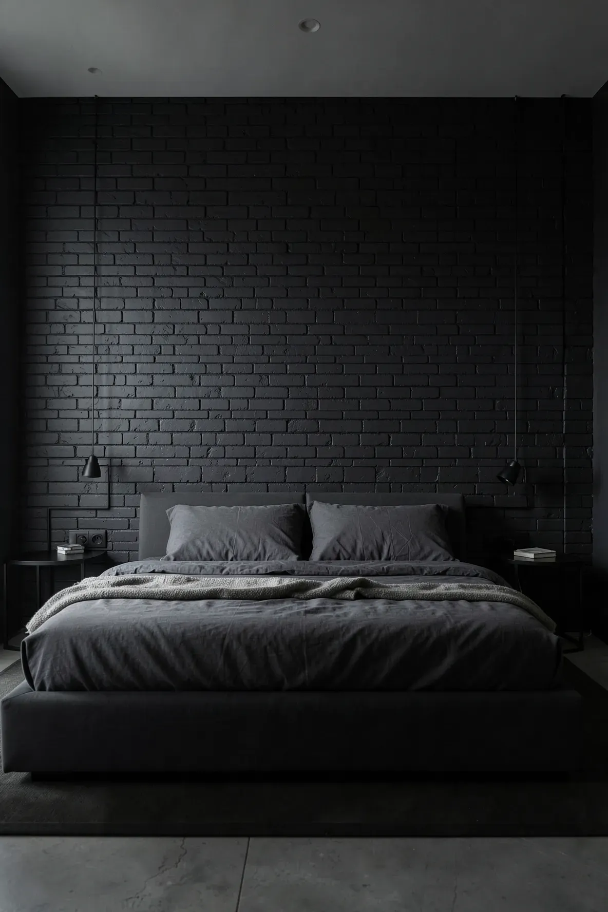 An accent wall of exposed brick painted matte black in a modern, moody bedroom.