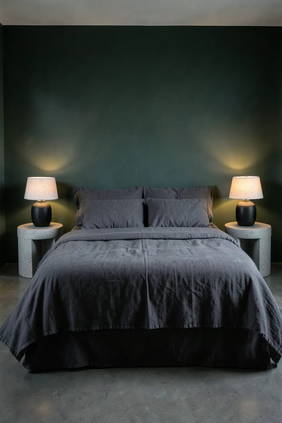 Modern moody bedroom with raw concrete side tables and minimalist black ceramic lamps.