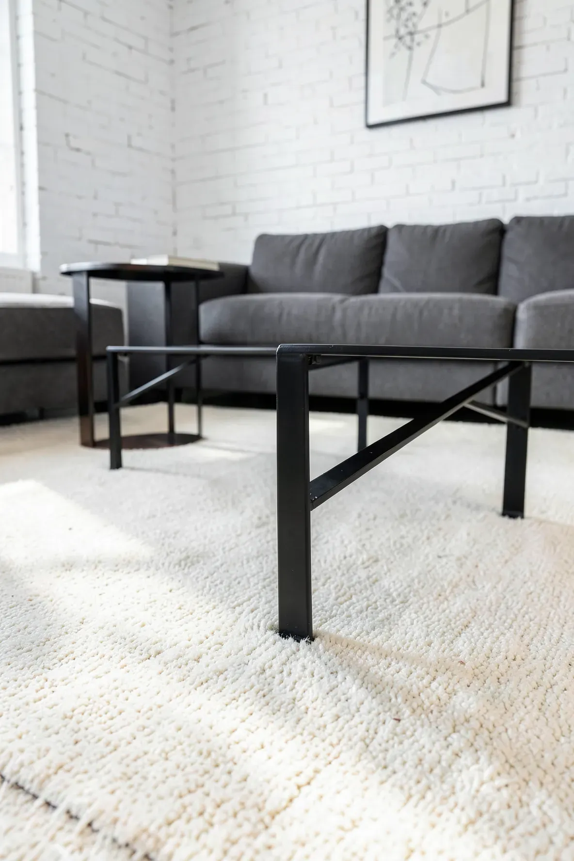 A black metal coffee table providing sharp contrast against a soft ivory area rug.