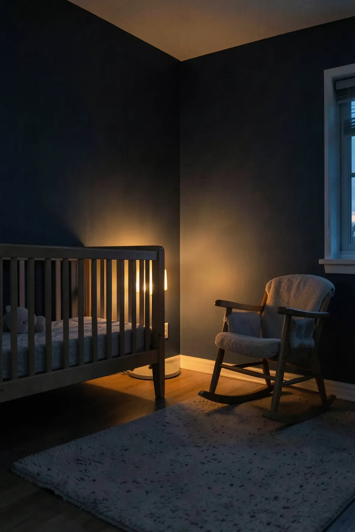A nursery at night illuminated by a soft, warm amber glow from a small floor-level nightlight.