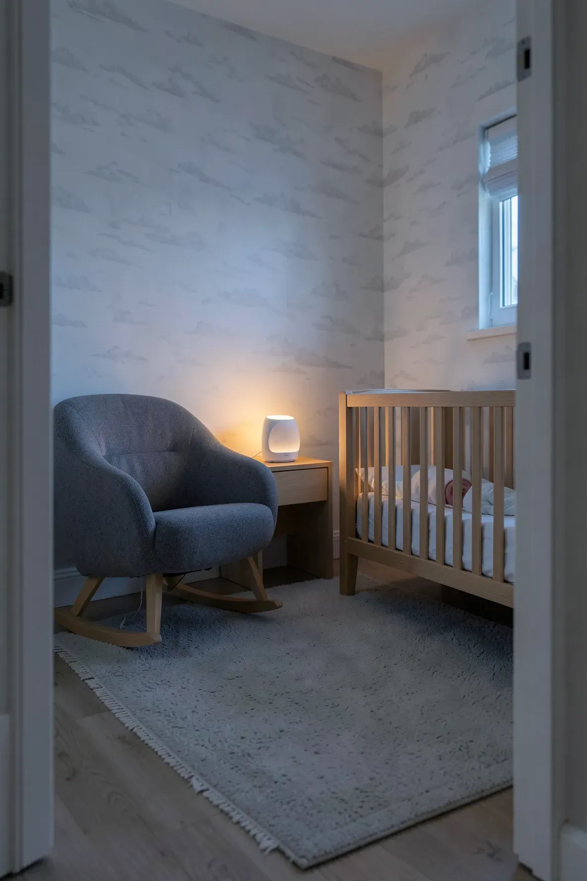 A modern white sound machine on a side table in a dimly lit, serene baby nursery.
