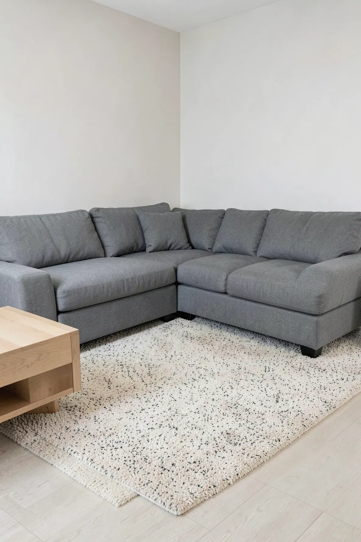 A steel gray sectional sofa on a durable speckled beige performance rug in a clean living room.