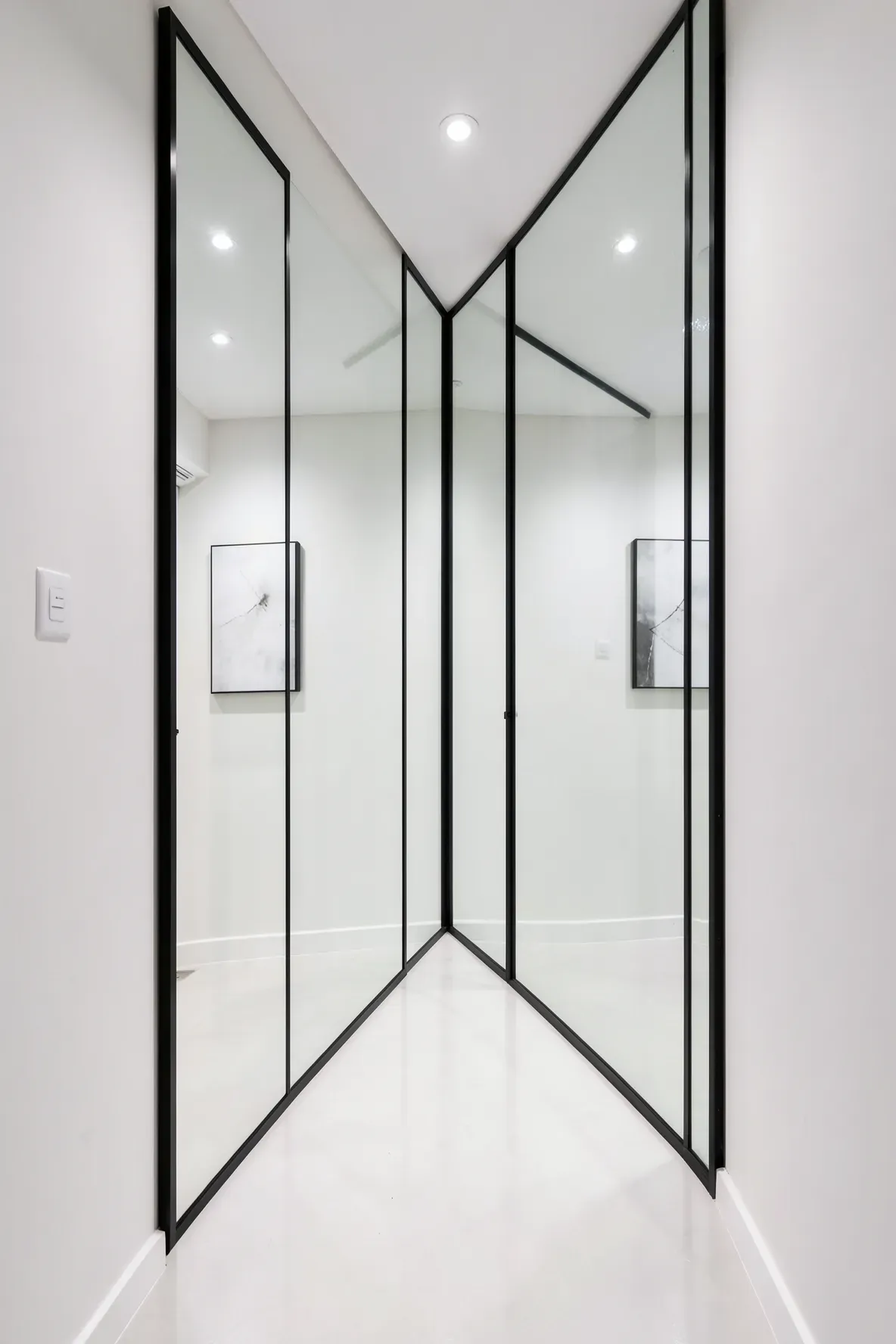 A large oversized mirror on a hallway wall reflecting the opposite side to make the space feel twice as wide.