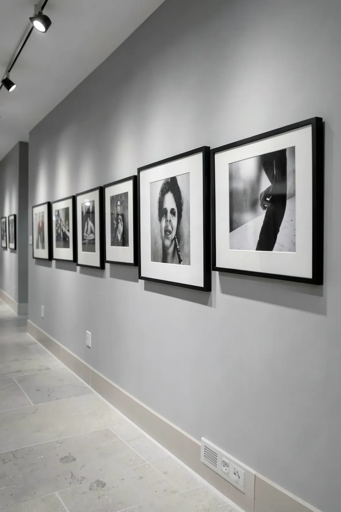 A series of identical black and white framed photos hanging in a row along a narrow hallway wall.
