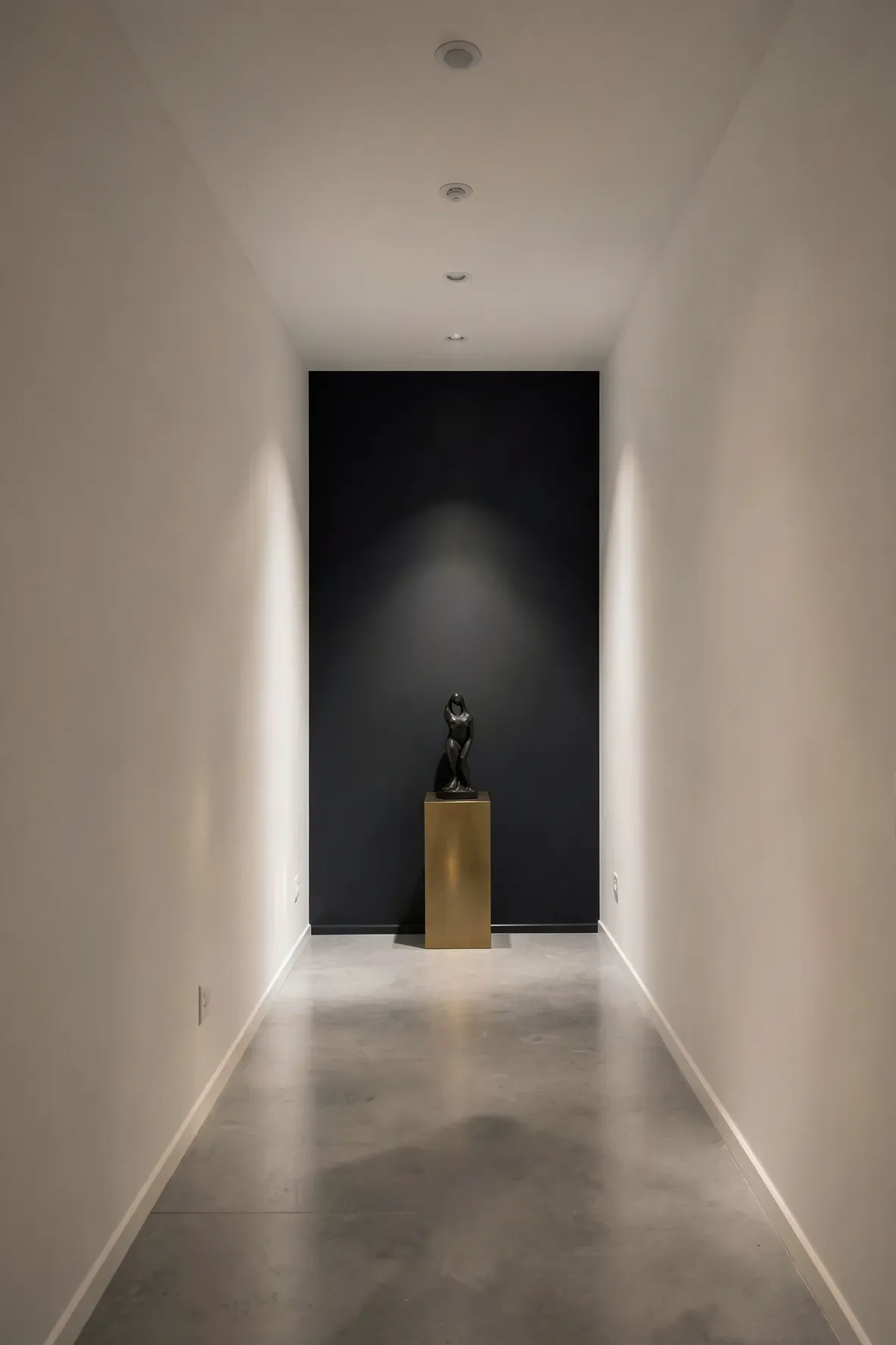 A long hallway with white side walls and a dark charcoal accent wall at the far end.