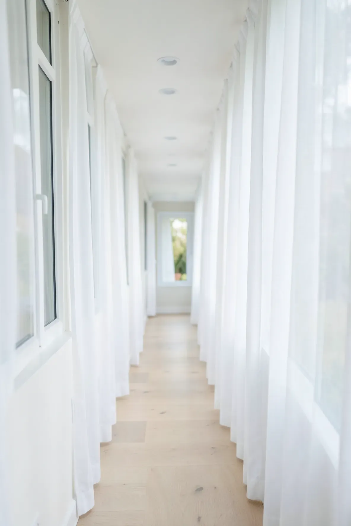 Sheer white curtains on hallway windows letting in soft natural light.