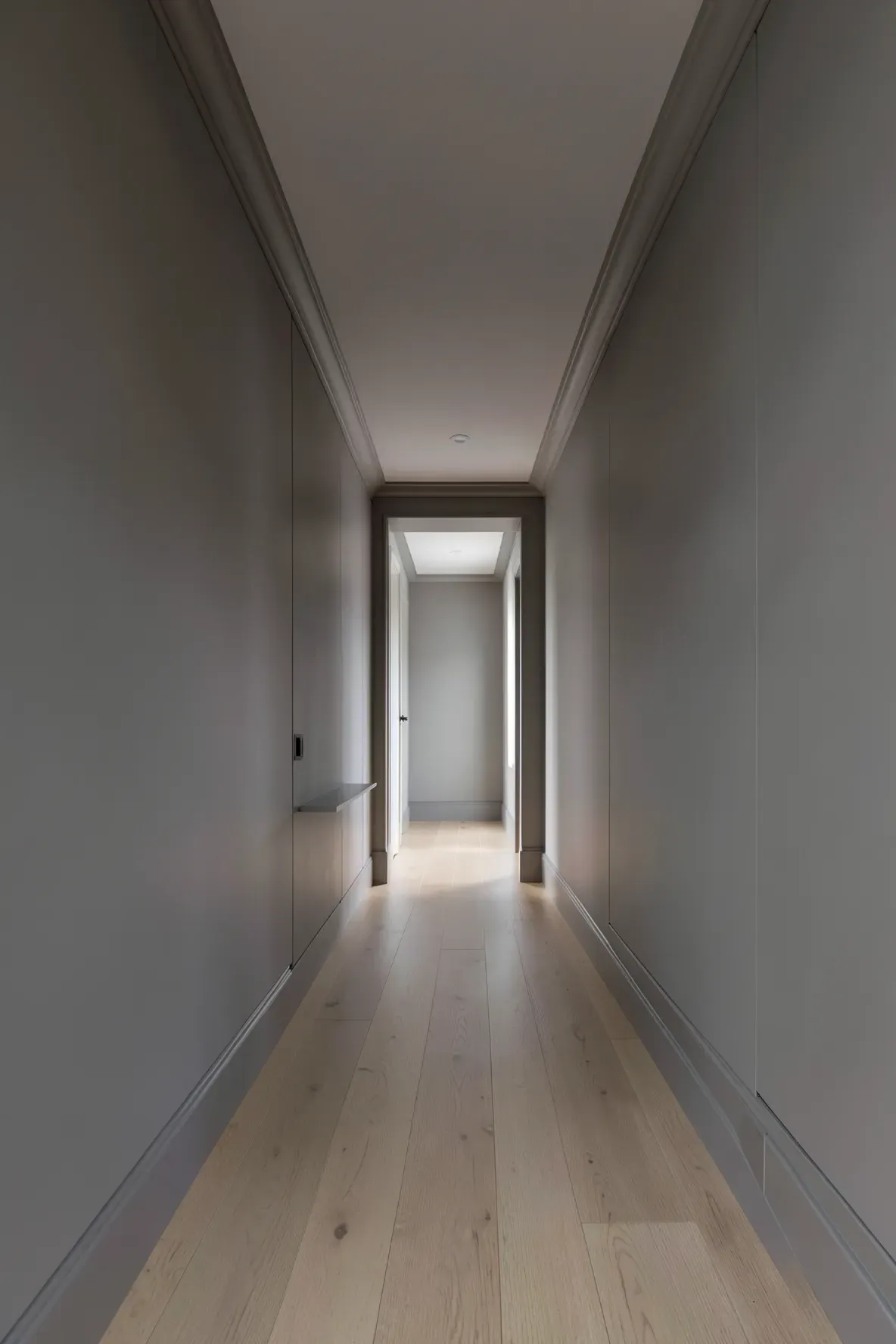 A long narrow hallway with walls and furniture painted in a matching mushroom-grey monochromatic palette.