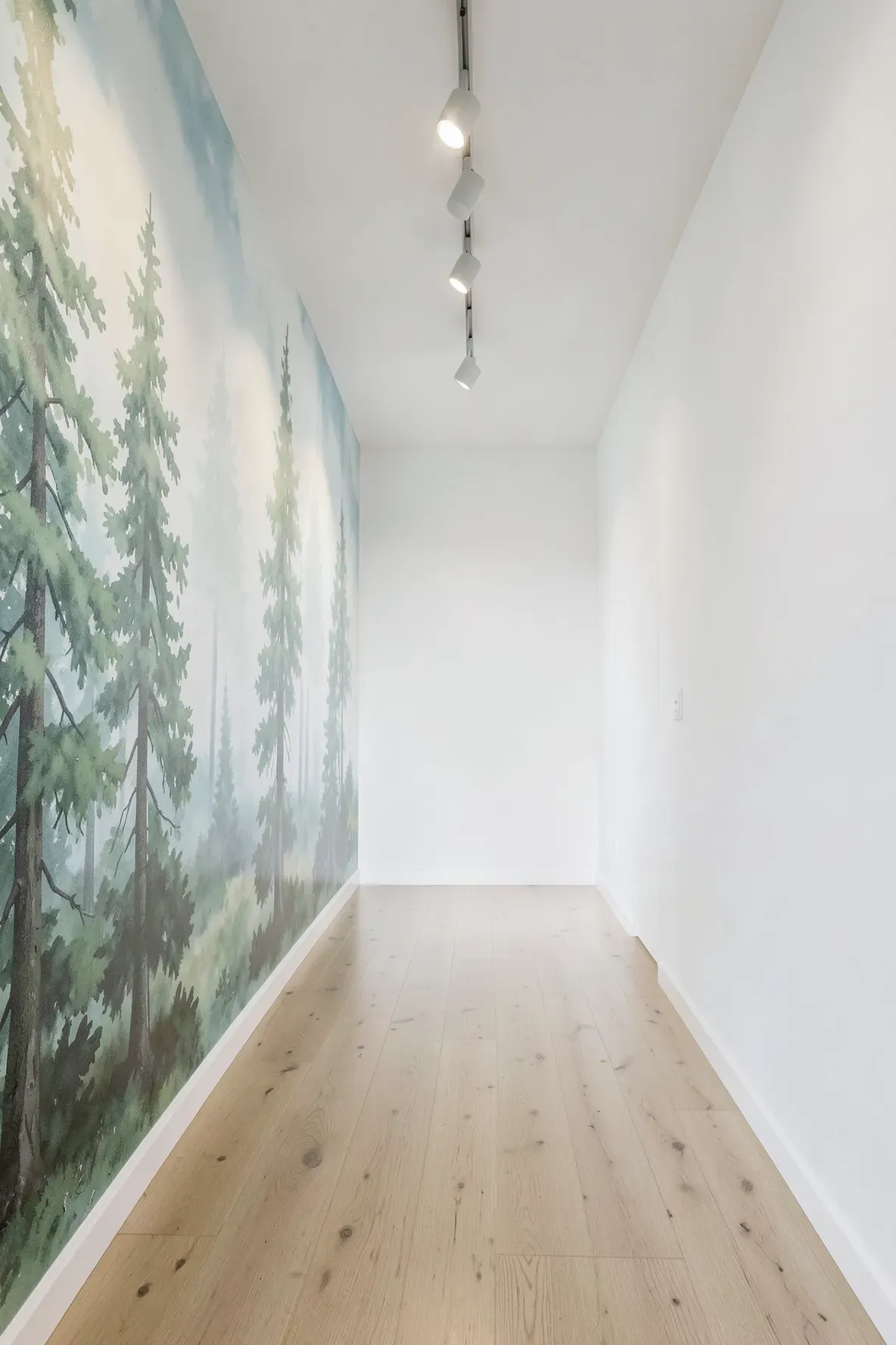 A long hallway featuring a misty forest mural on one wall to create a sense of depth.