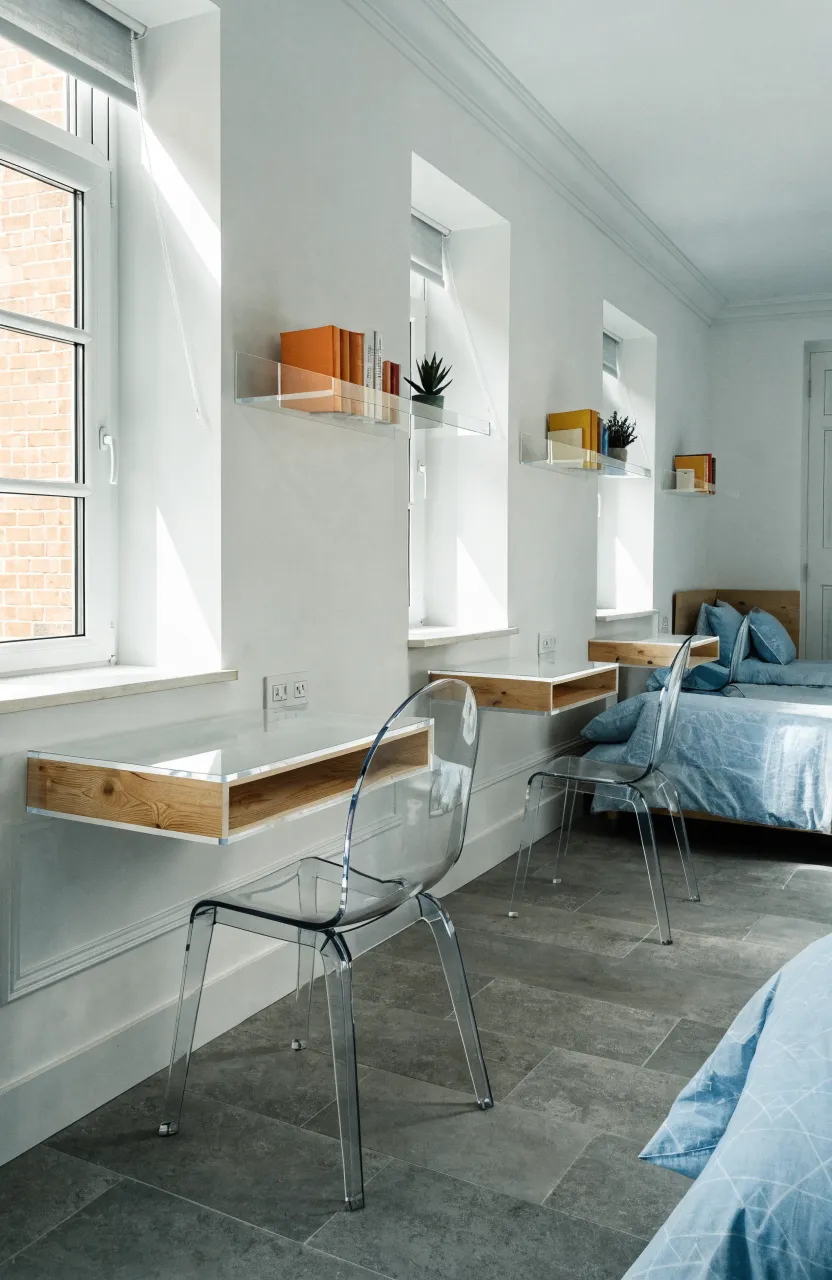 Three slim, white wall-mounted floating desks arranged in a row for a shared sisters' study area.