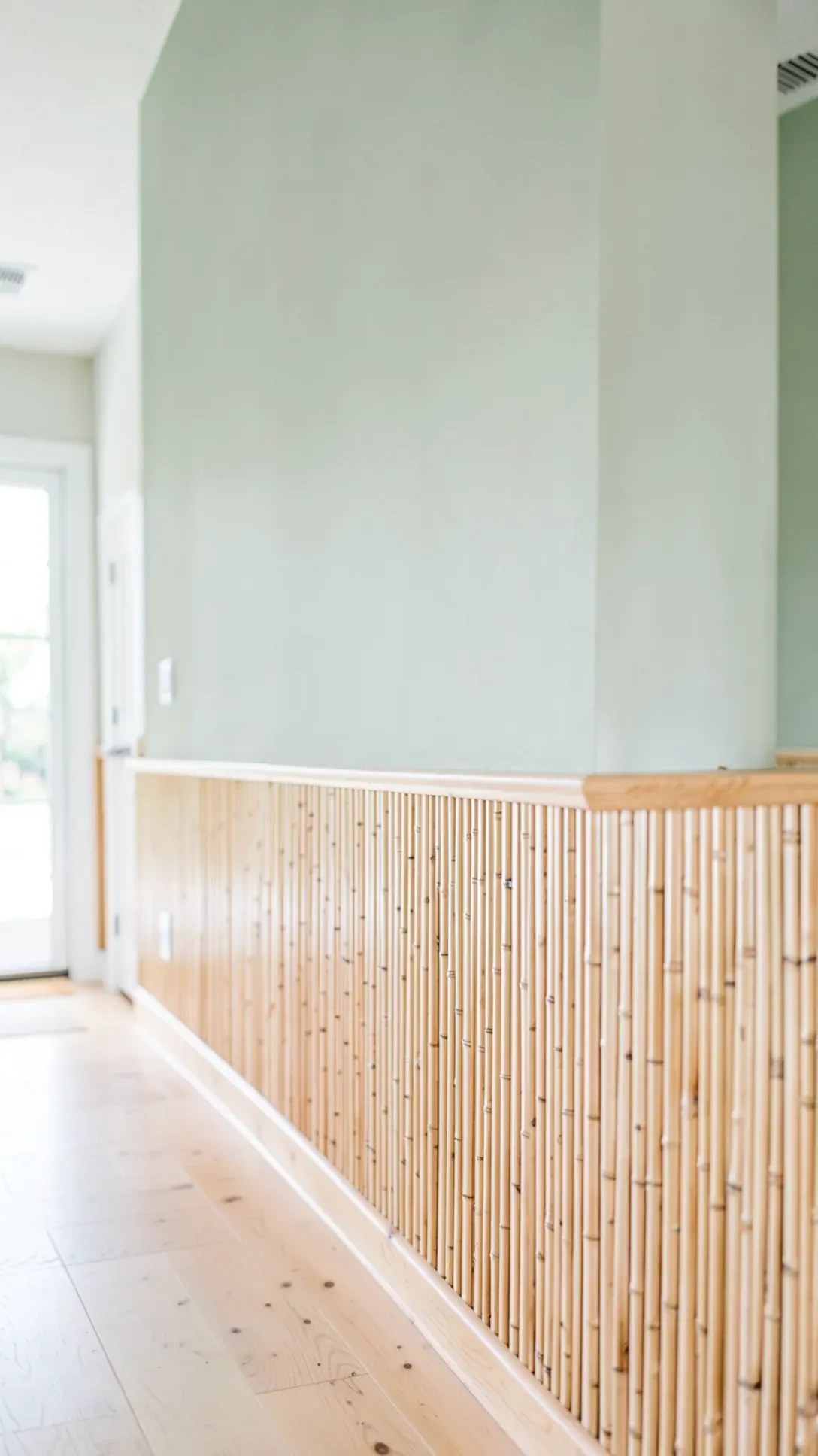 Lower wall covered in vertical bamboo slats with a wooden rail and sage green paint above.