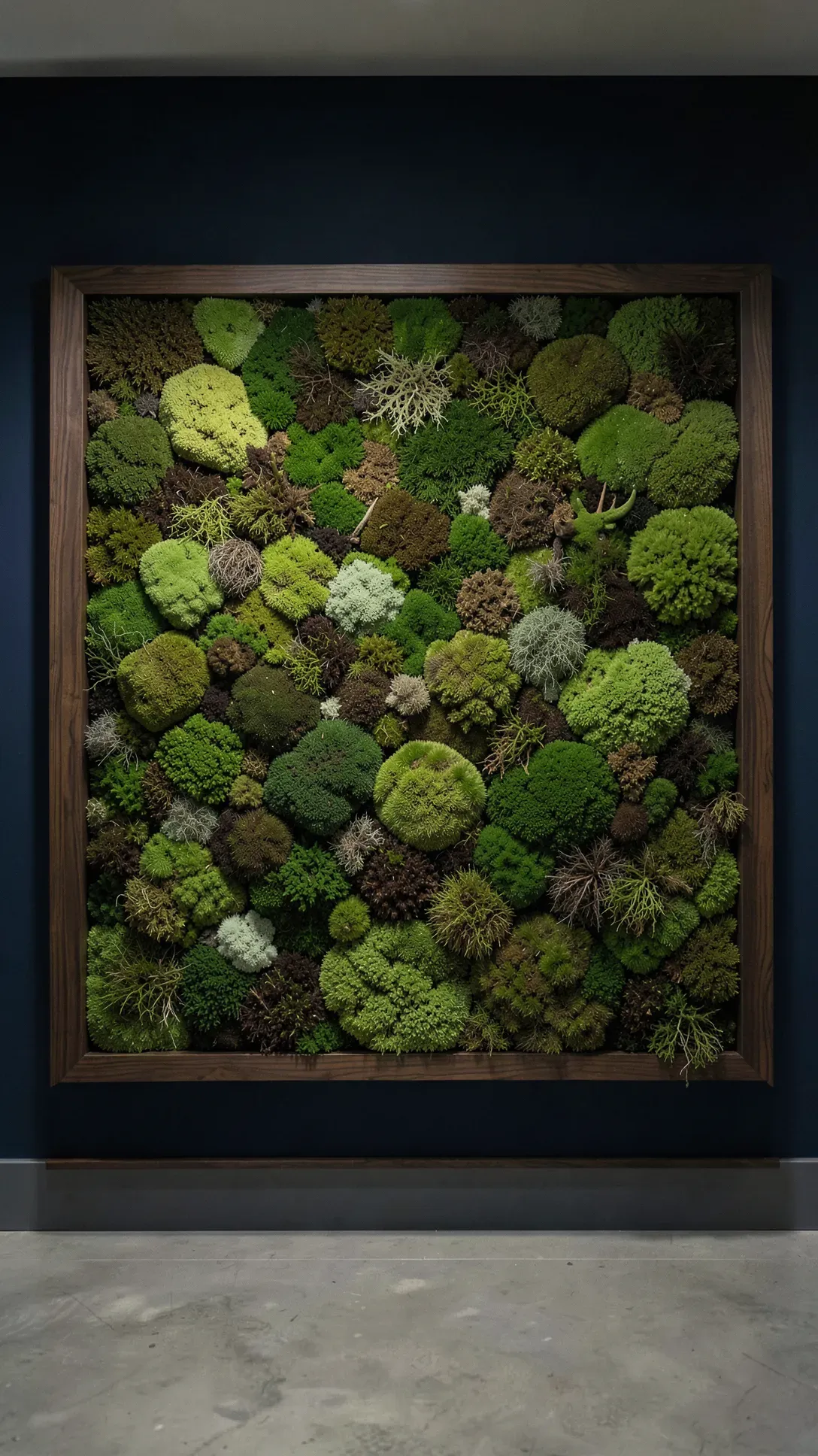 A large walnut-framed panel of preserved green moss textures mounted on a dark navy blue wall.