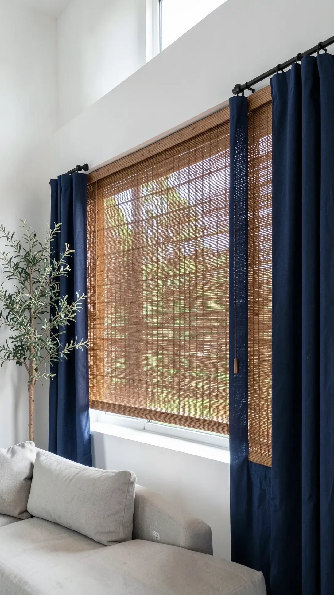 Woven bamboo blinds paired with navy blue linen side panels in a modern living room.