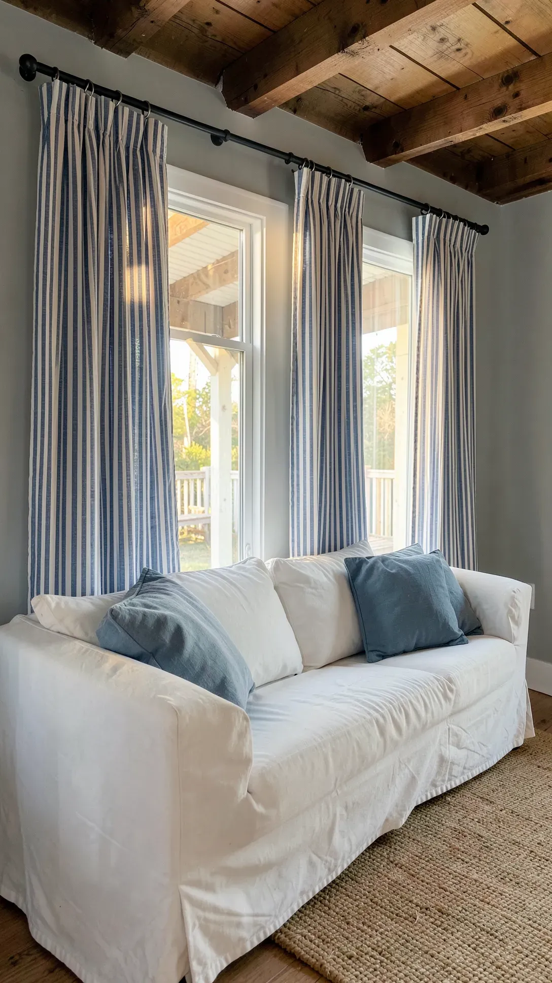 Blue and white ticking stripe curtains on a black rod in a casual farmhouse living room.