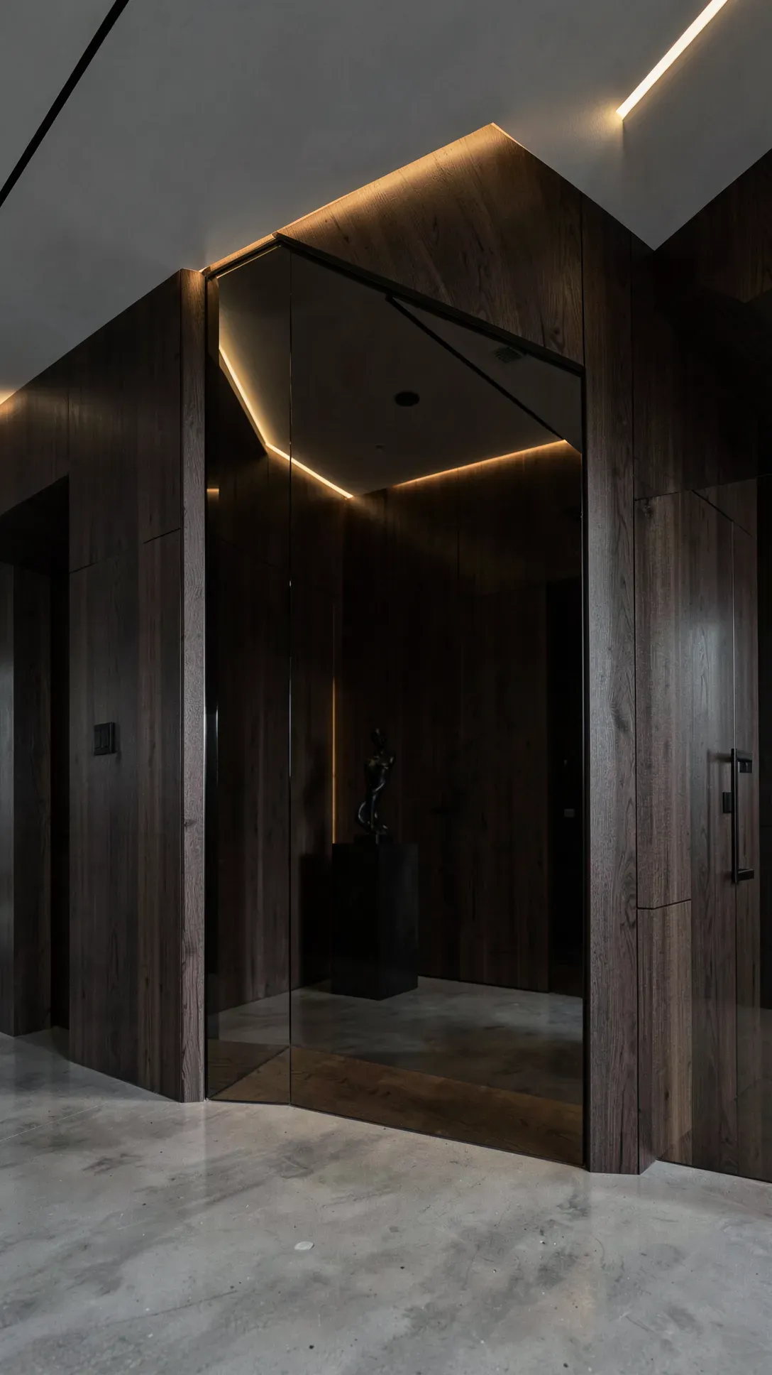 A large floor-to-ceiling smoked bronze mirror in a dark, moody, and luxurious modern foyer.
