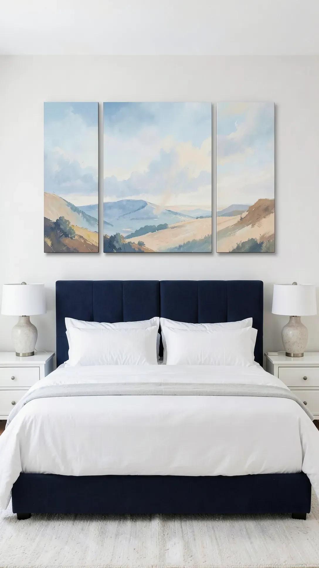 Three abstract landscape paintings in blue and beige hanging in a row above a bed.