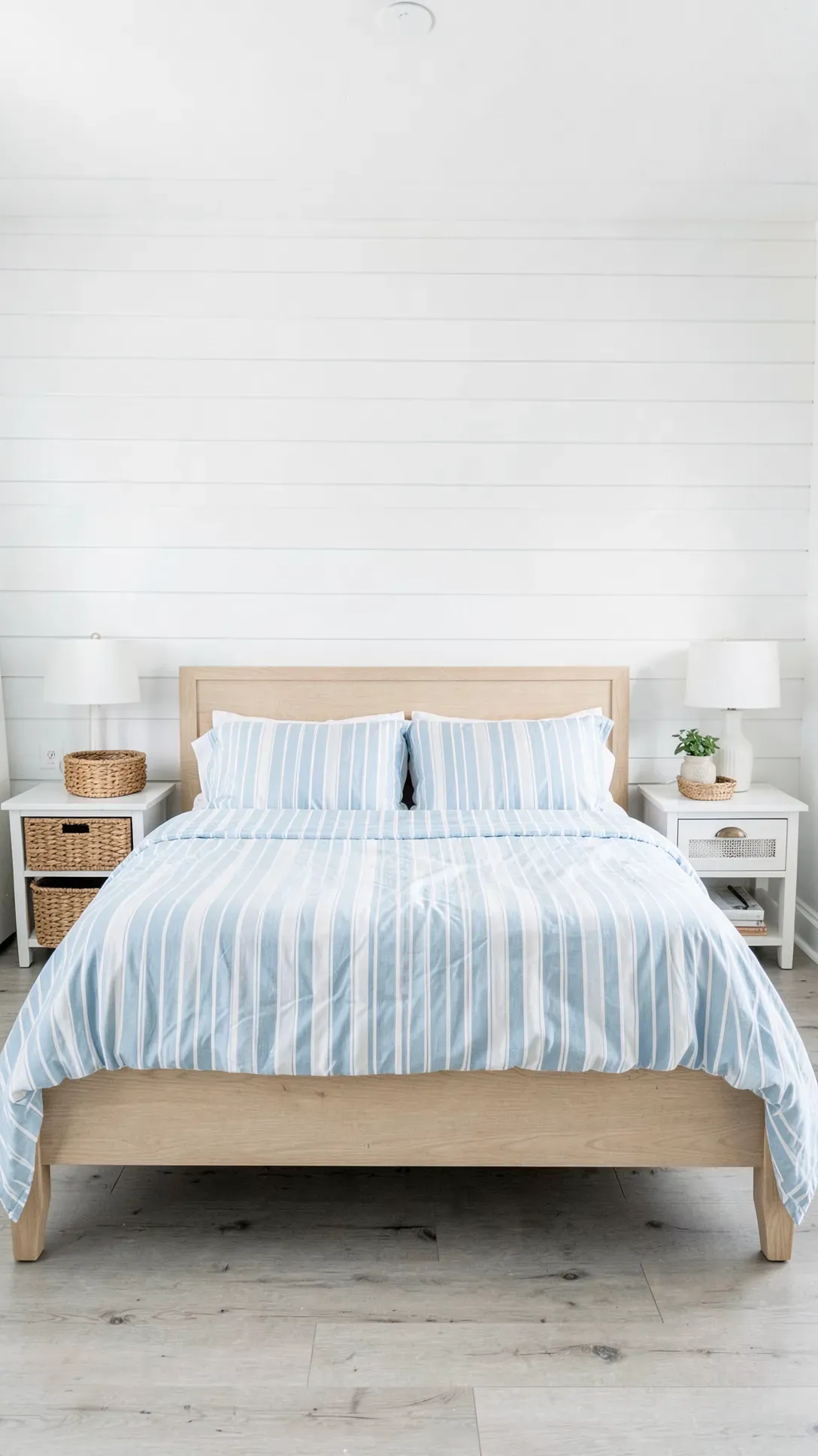 A bright bedroom with white horizontal shiplap walls and coastal-style blue bedding.