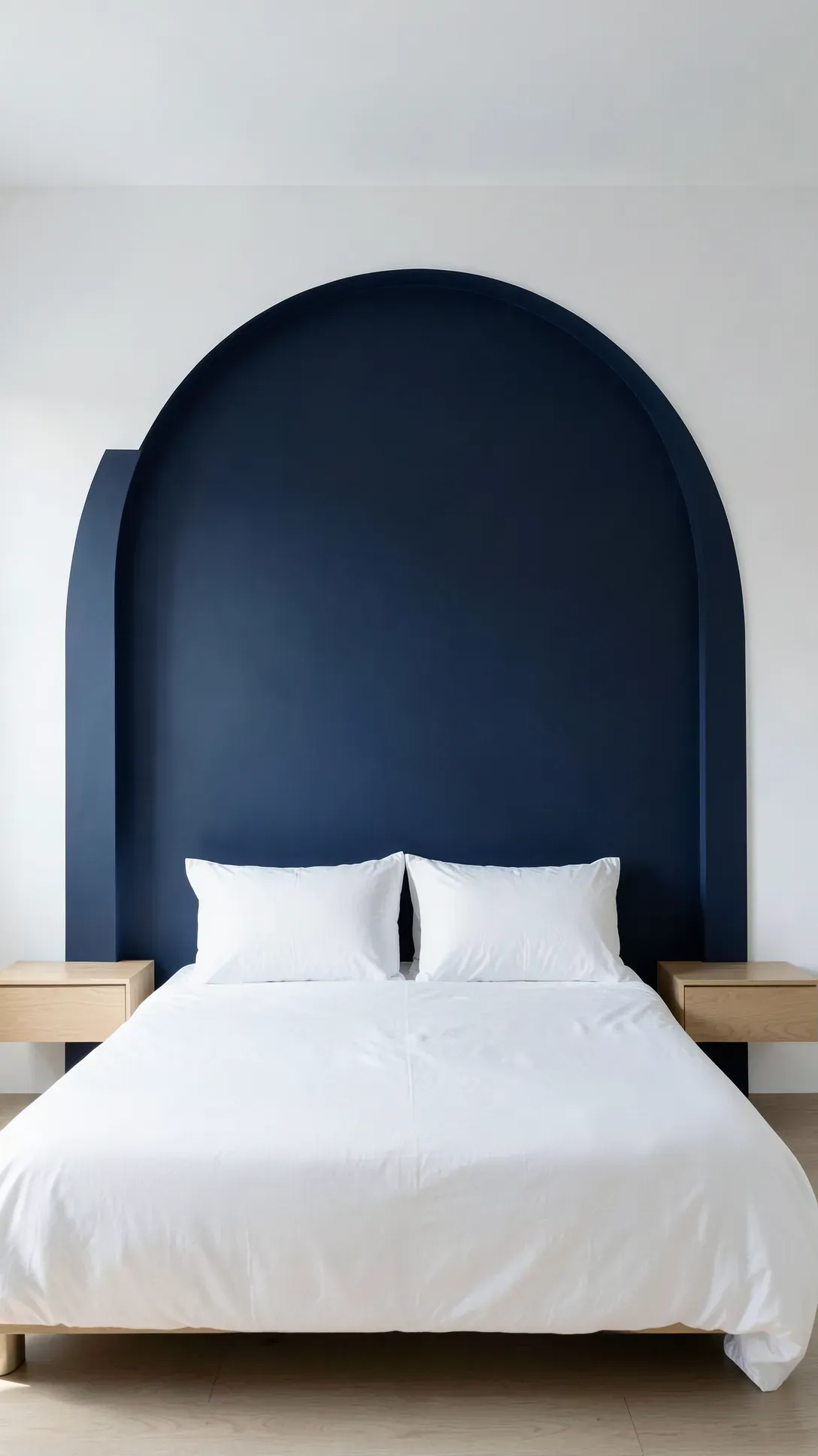 A large navy blue arch painted on a white wall behind a bed to look like a headboard.