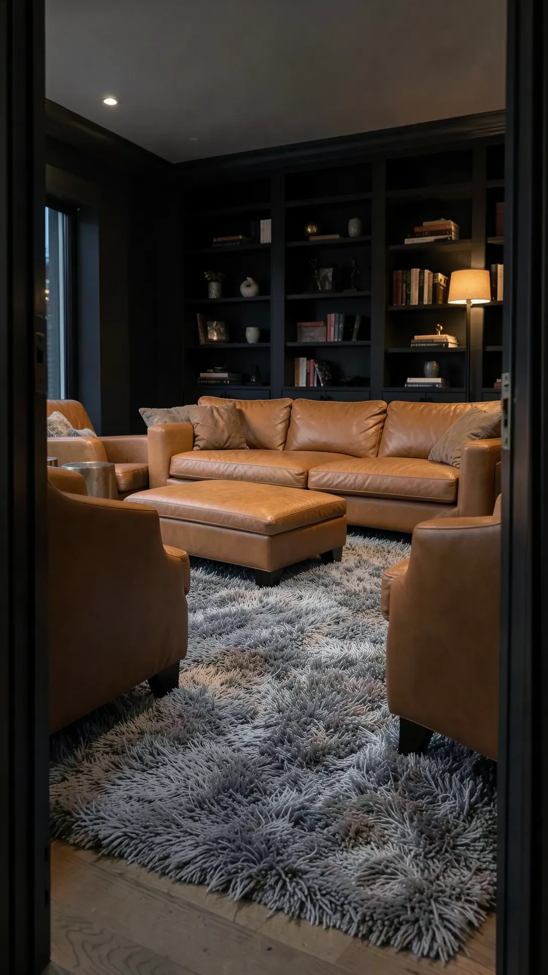 A plush grey shag rug paired with tan leather seating in a moody, cozy den.