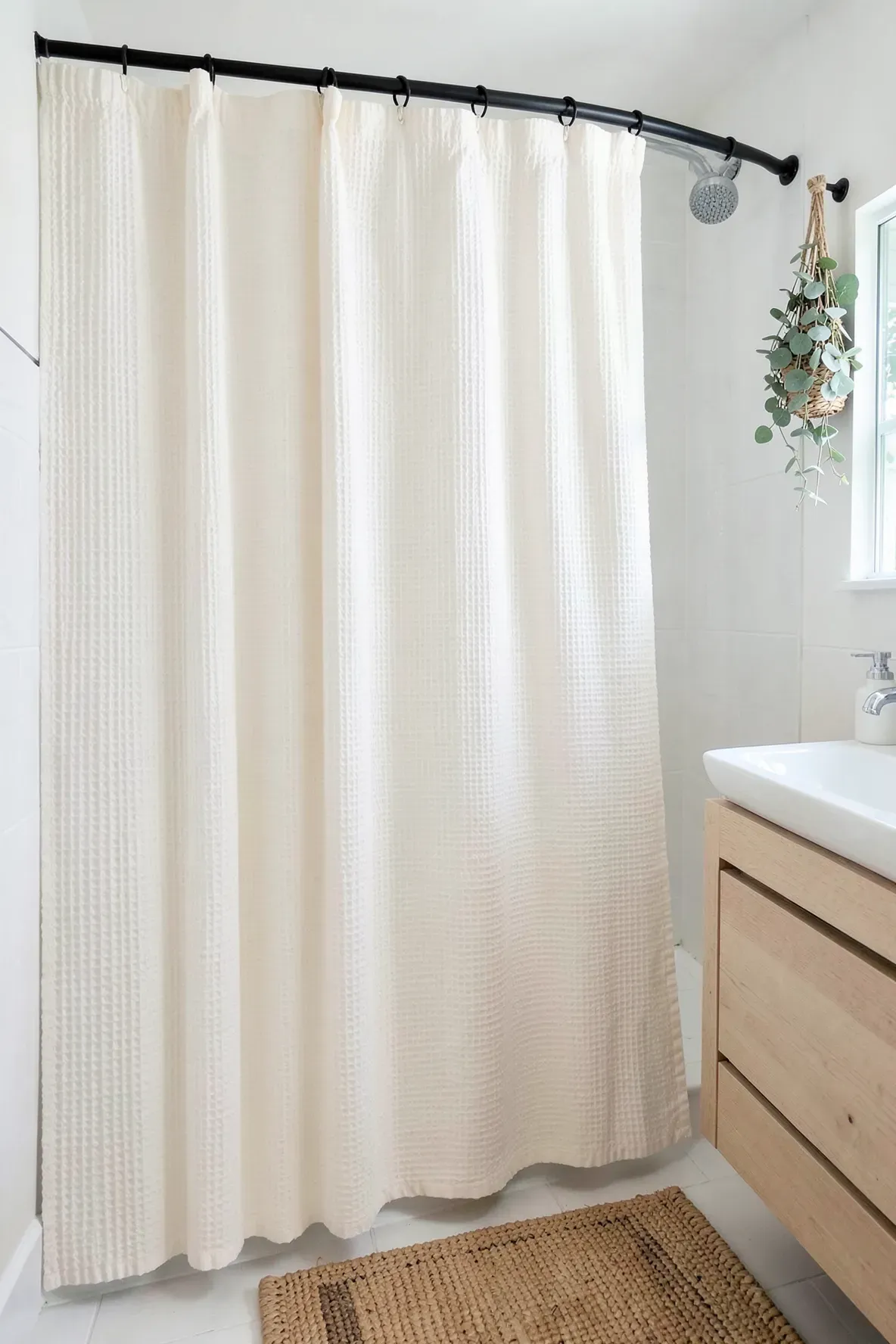 A textured cream waffle weave shower curtain in a bright, minimalist boho bathroom.