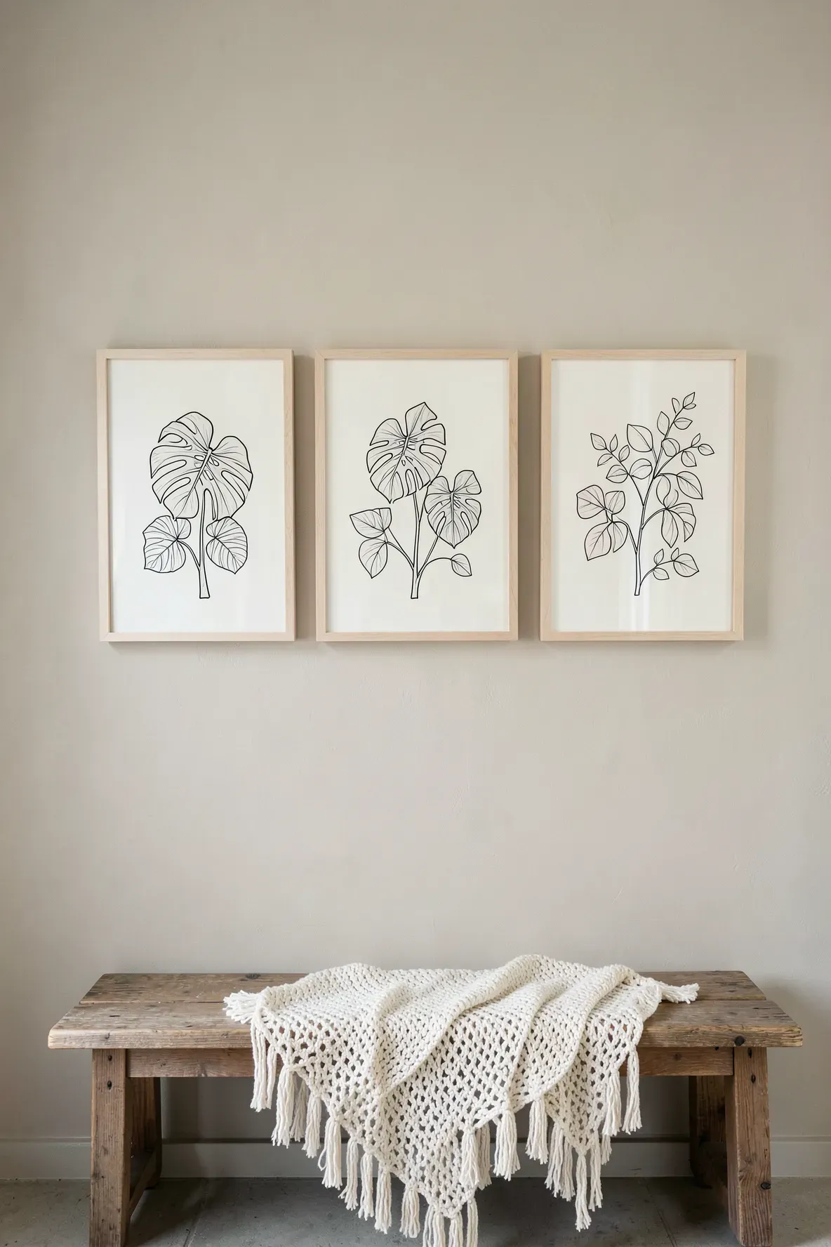 Three framed botanical line art prints hanging on a beige wall in a boho bathroom.