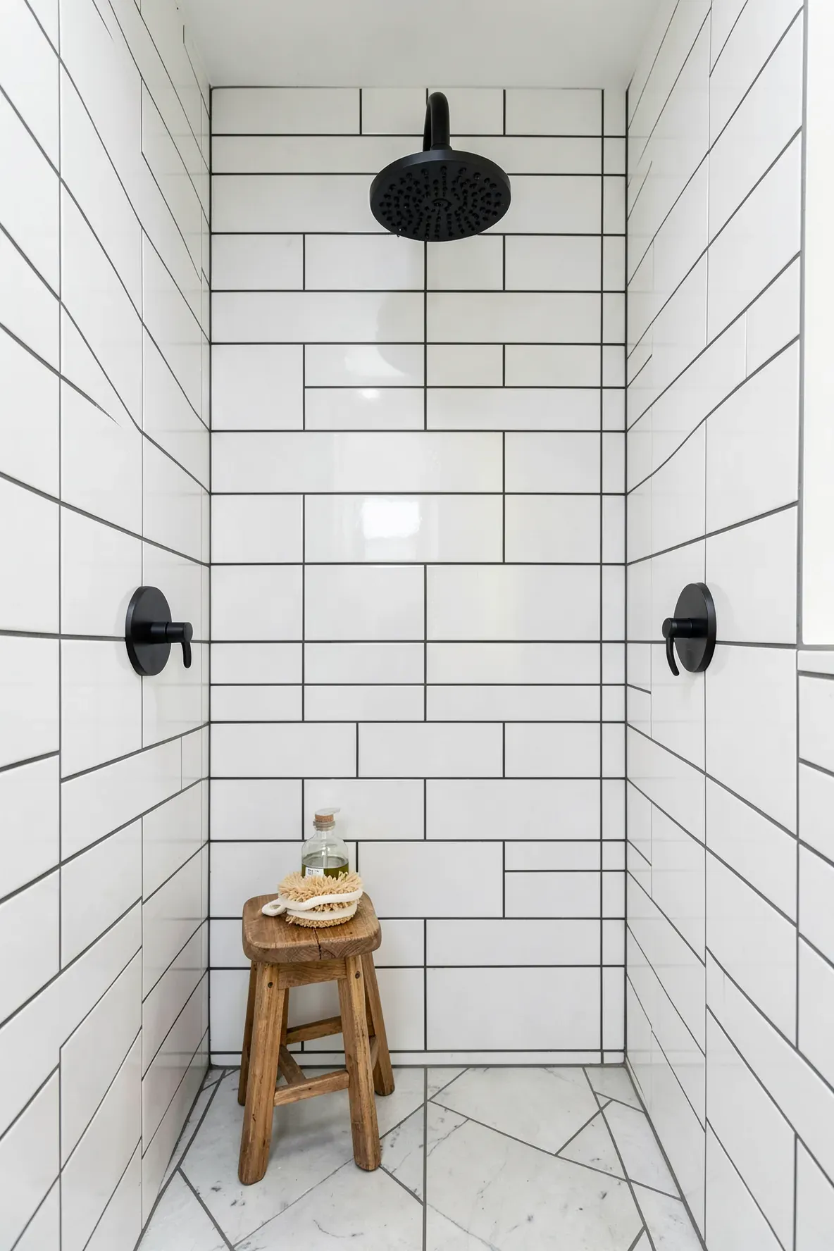 A modern matte black rainfall shower head set against white subway tiles in a bohemian bathroom.