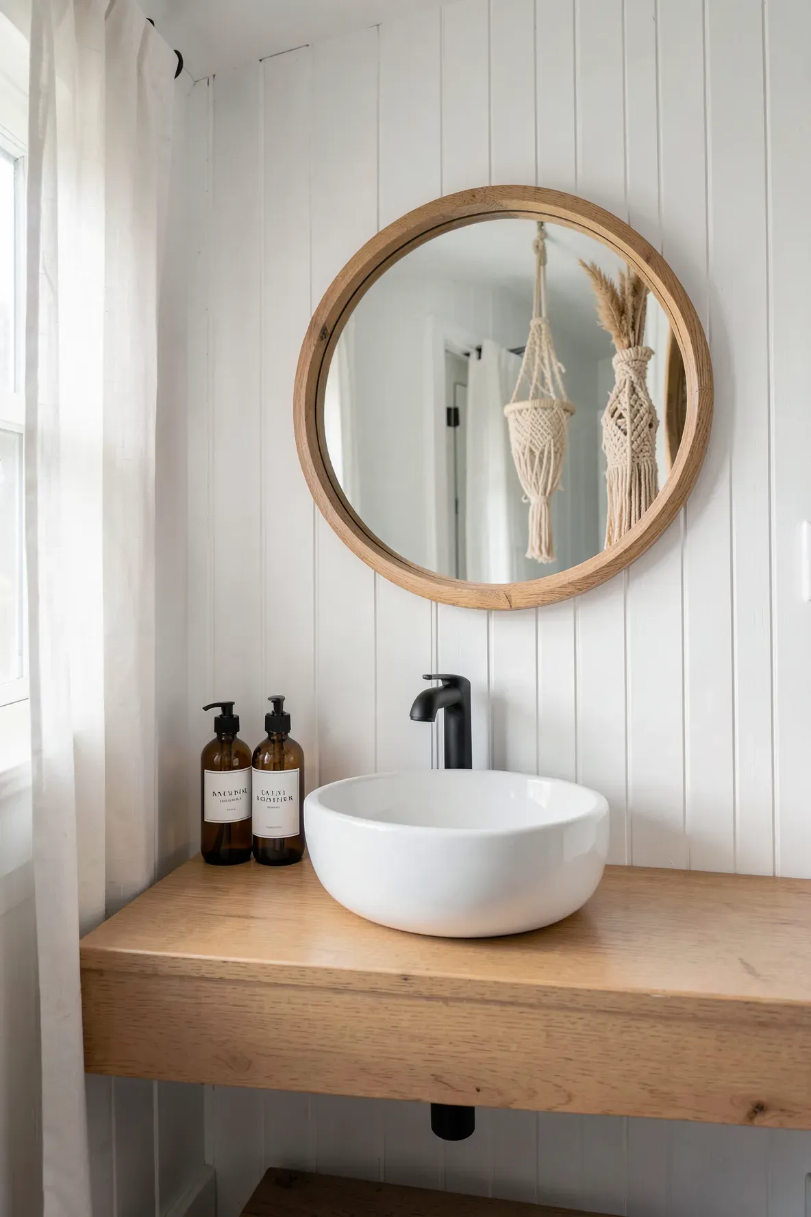 Three amber glass soap bottles with white labels on a wooden bathroom vanity with a white sink.