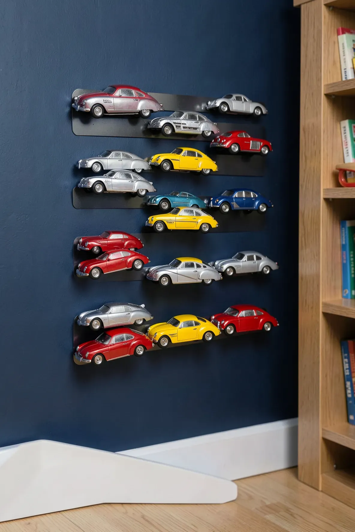 Dozens of colorful metal toy cars stuck to magnetic strips mounted on a navy blue wall.