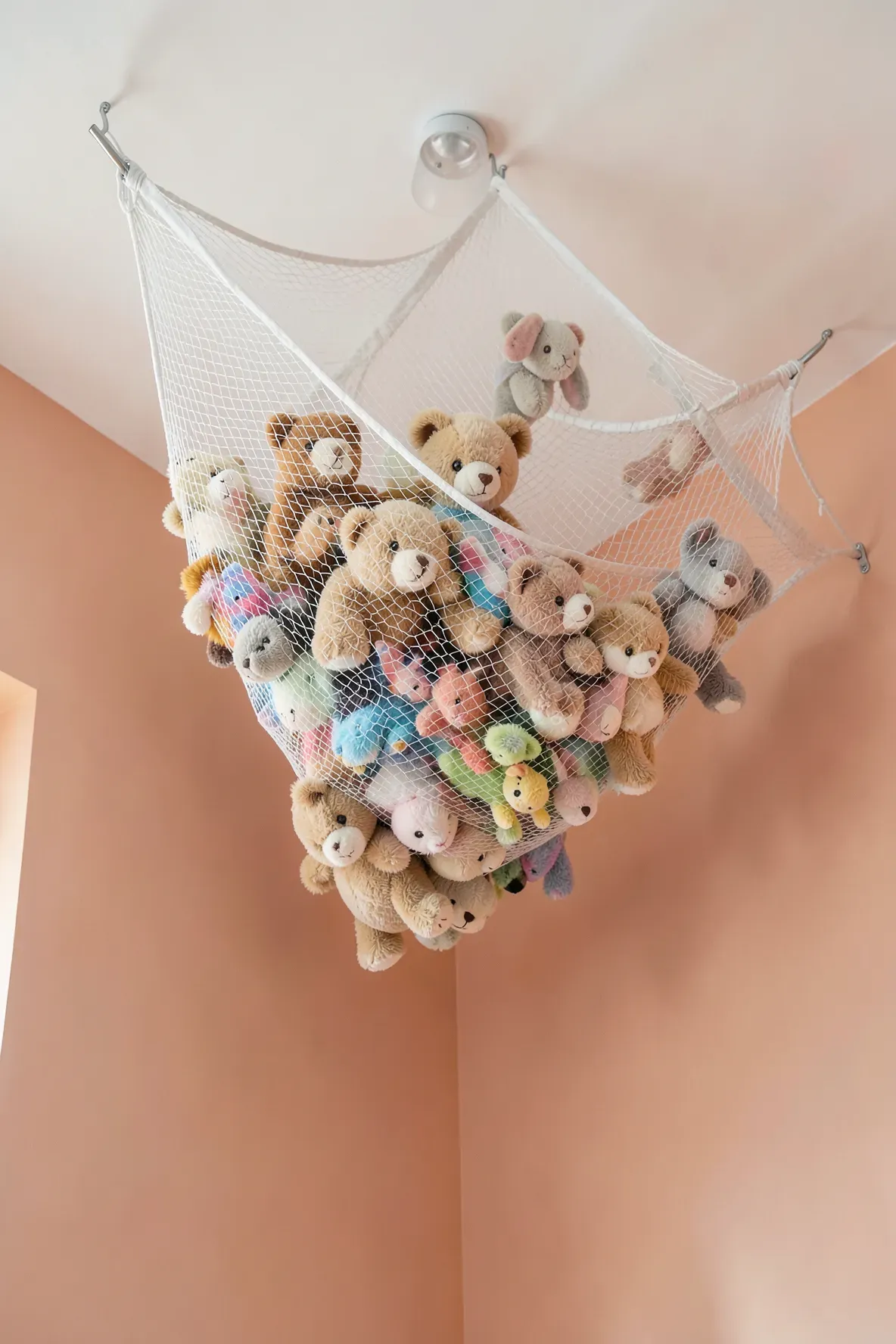 A white mesh net in the corner of a room filled with many colorful stuffed animals.