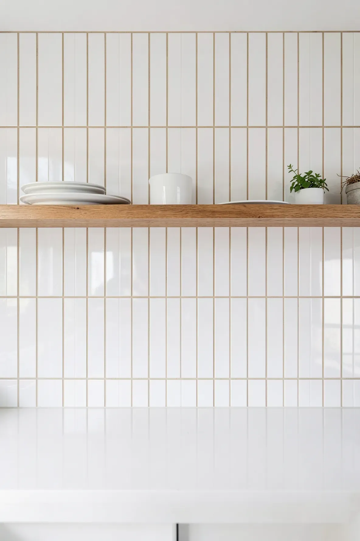 Vertically stacked white subway tiles with sandy beige grout in a modern coastal kitchen.