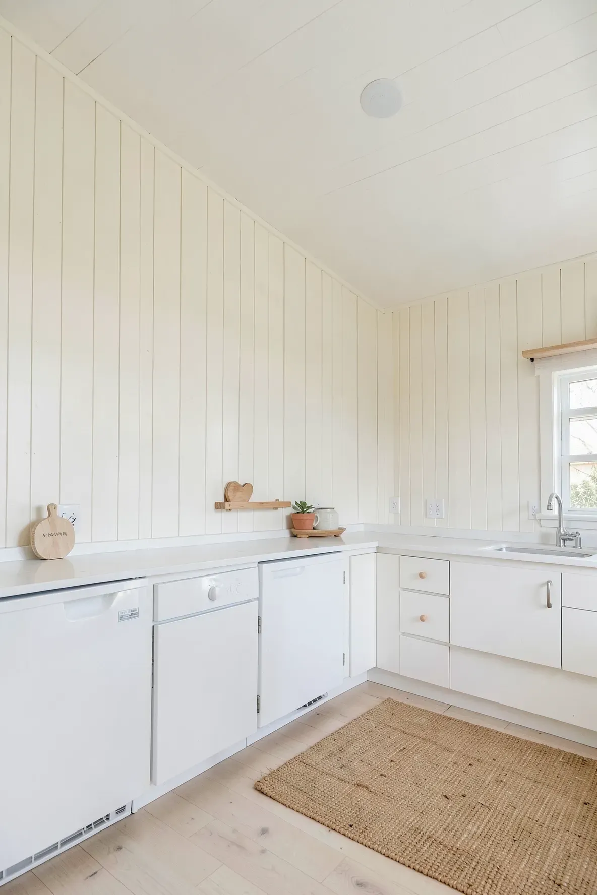 A bright kitchen with vertical shiplap walls painted in soft white for a coastal boho look.