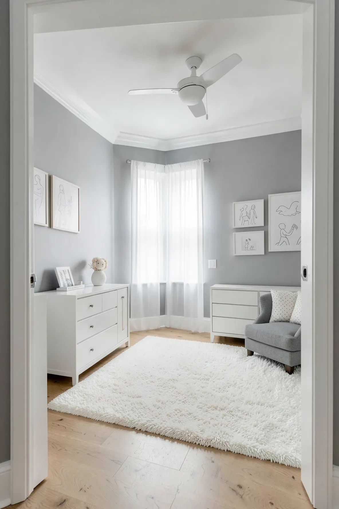 A modern nursery room with soft gray walls, white trim, and a bright, airy atmosphere.