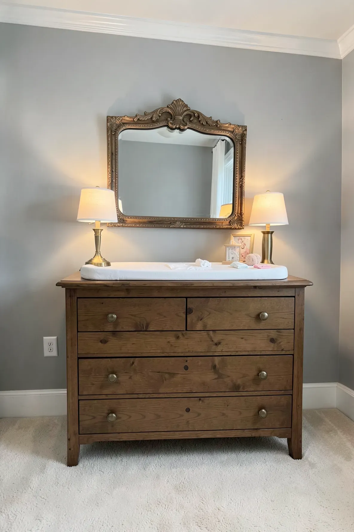 A walnut wood dresser with a changing pad on top in a classically designed nursery.