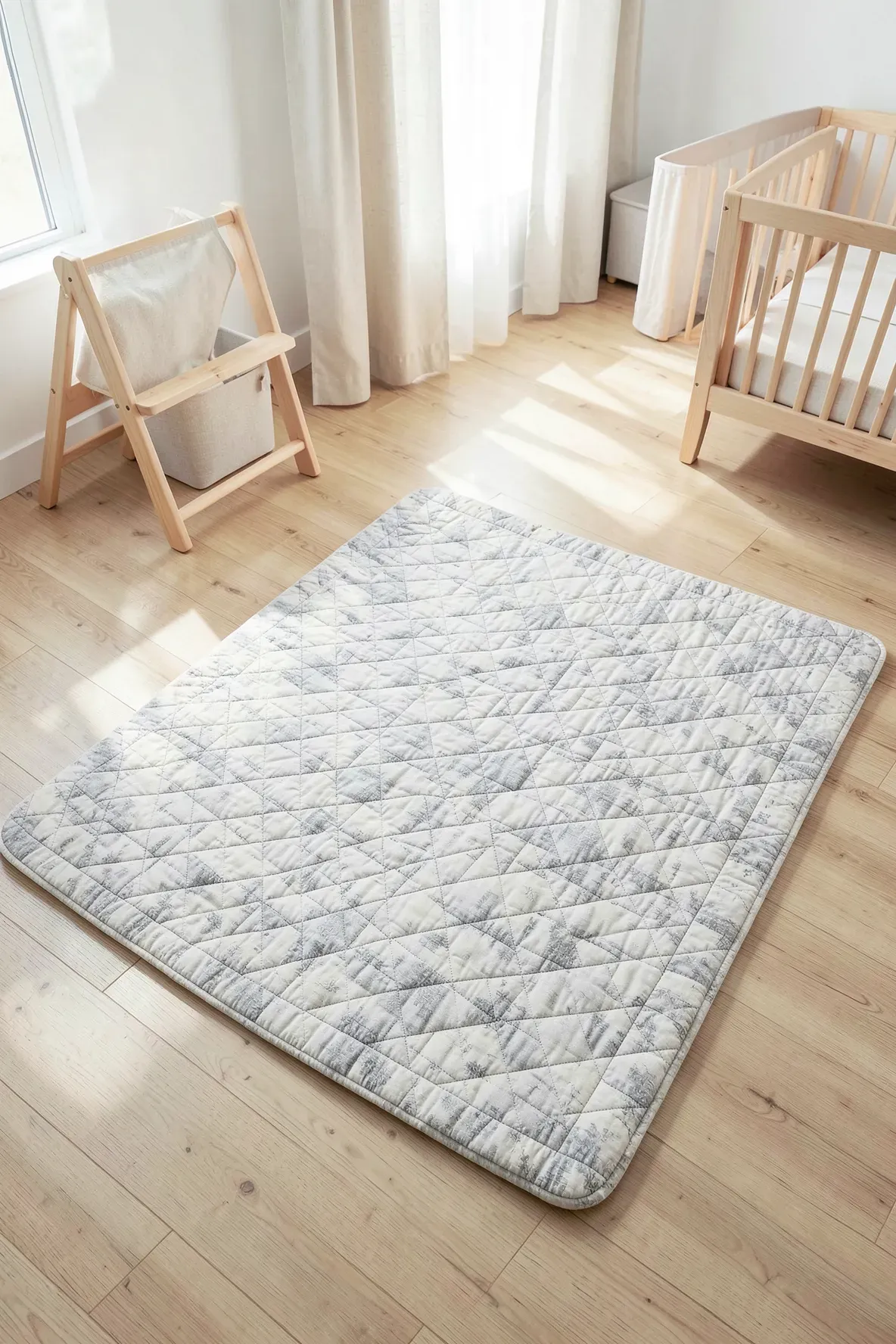 A plush, grey and white quilted floor mat in the center of a bright, modern nursery room.
