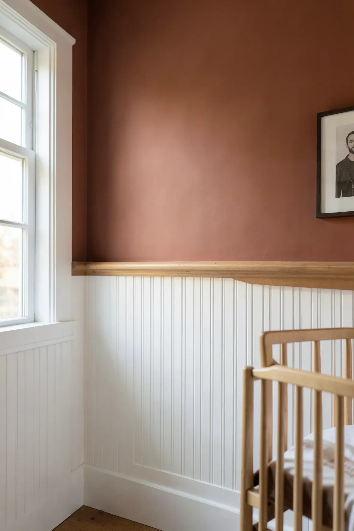 White beadboard wainscoting on the lower half of a terracotta-colored nursery wall.