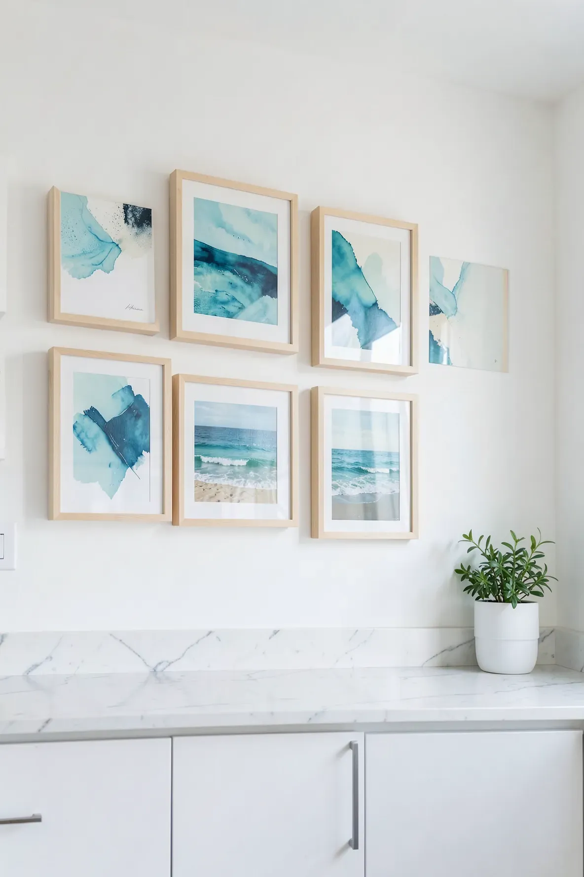 Abstract blue ocean prints in light wood frames hanging on a white kitchen wall.