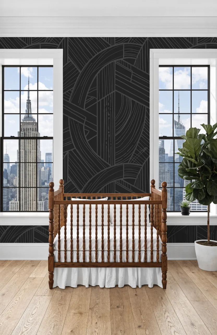 A modern walnut crib against a grey and white geometric patterned accent wall.