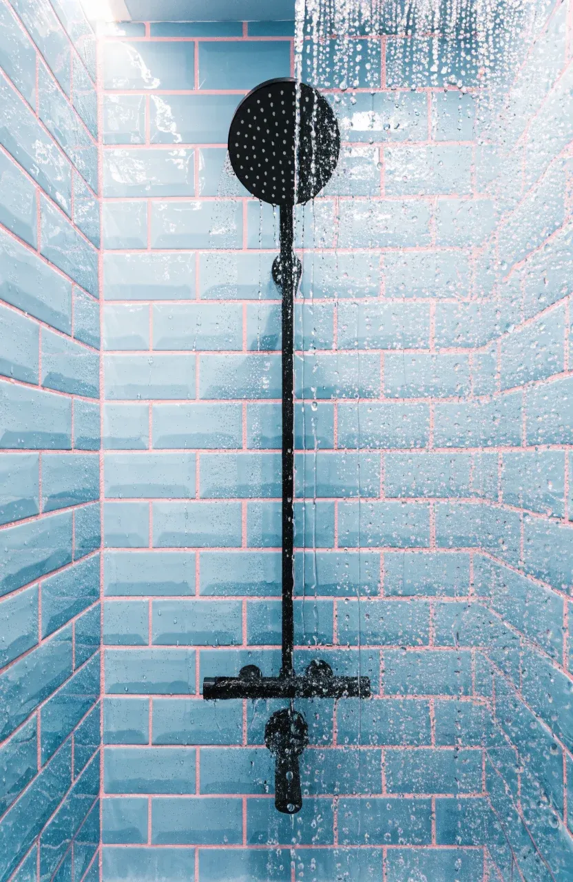 Pastel blue subway tiles with vibrant pink grout in a modern walk-in shower.
