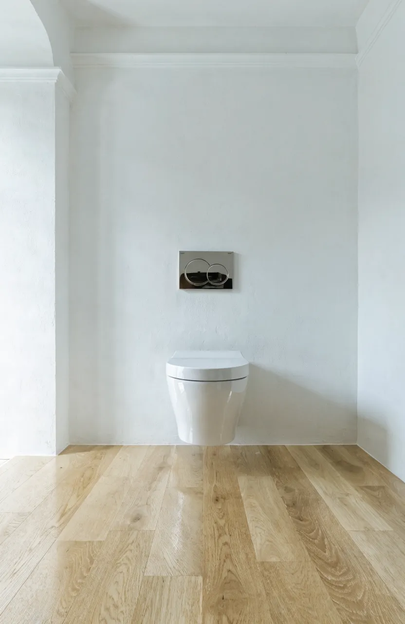 A wall-hung toilet with a hidden tank in a minimalist small bathroom design.