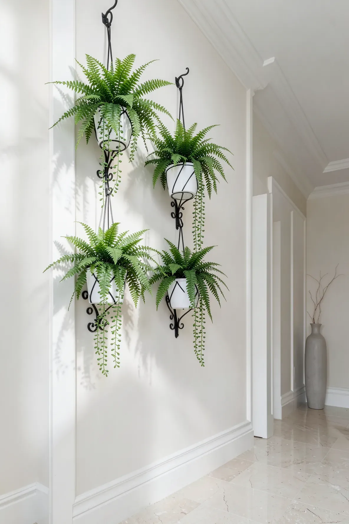 Faux hanging plants in white pots suspended from black metal brackets on a white wall.