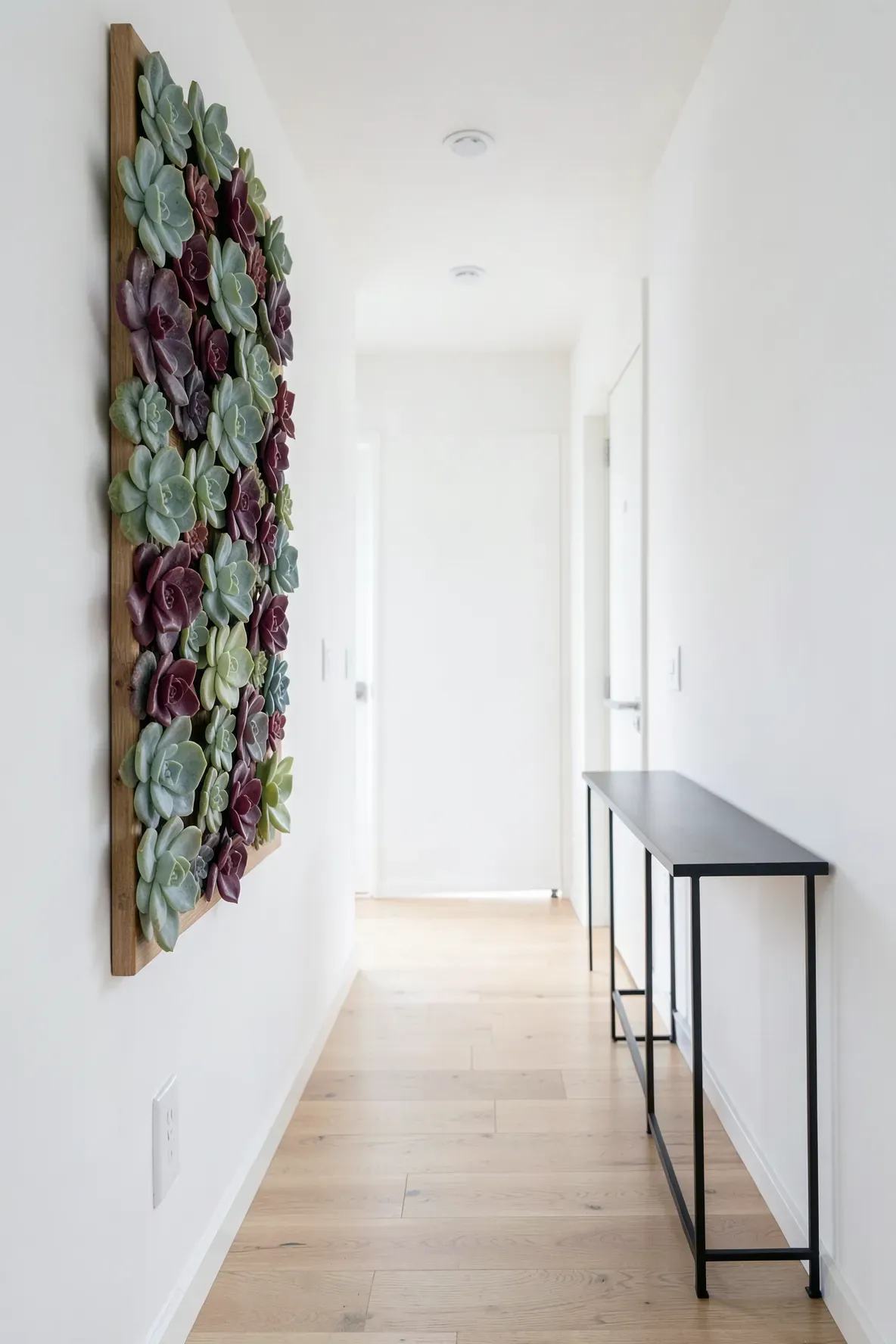 A vertical wooden frame filled with colorful faux succulents on a white entryway wall.