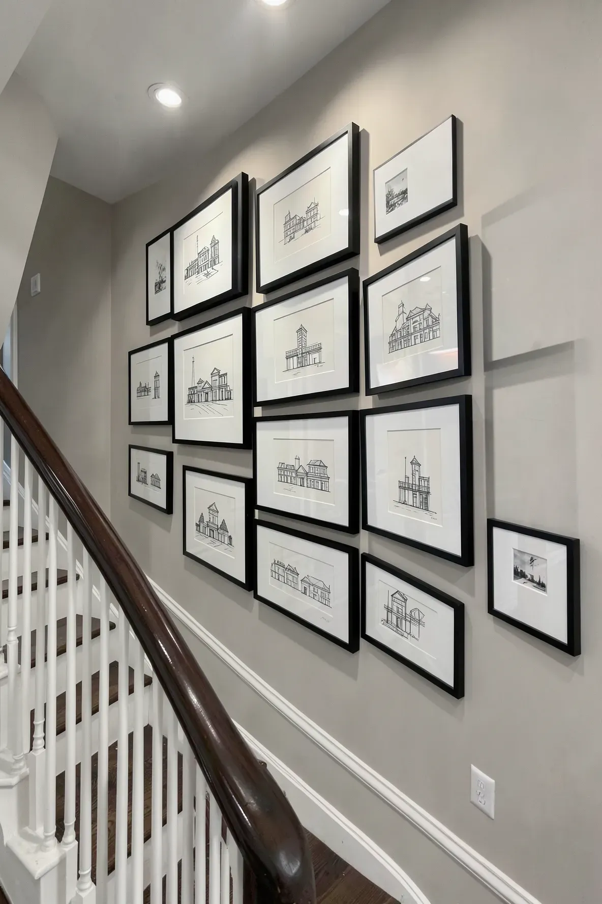 A series of uniform black picture frames arranged in a grid on a narrow hallway wall.
