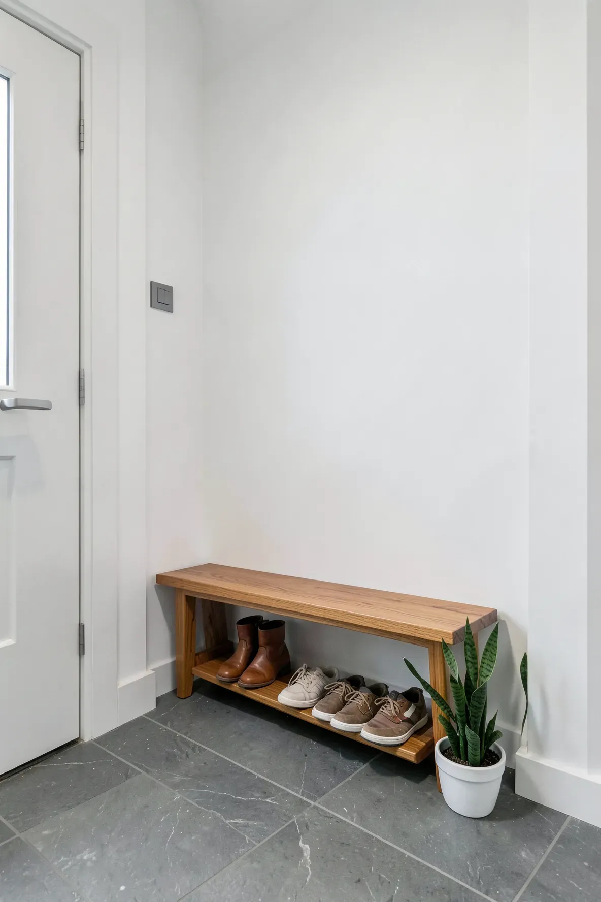 A slim wooden bench with a shelf for shoes underneath in a narrow, tidy entryway.