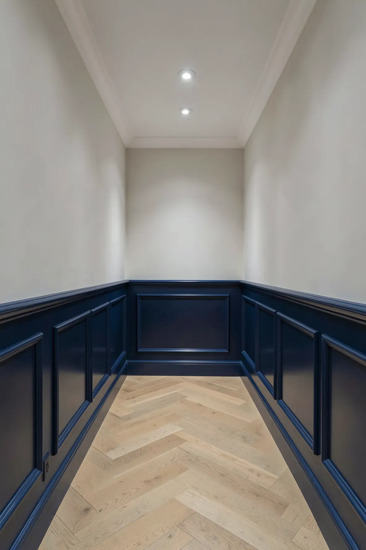Traditional navy blue wainscoting on the bottom half of a narrow hallway wall with light upper walls.