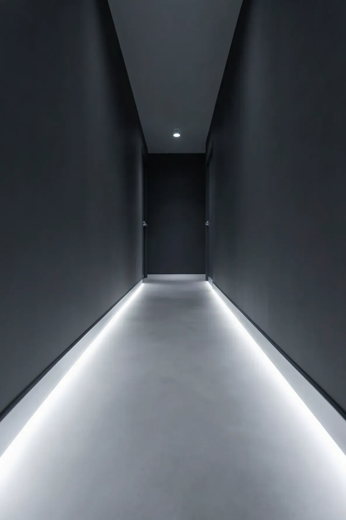 A modern narrow hallway with a glowing LED light strip installed along the base of the walls.