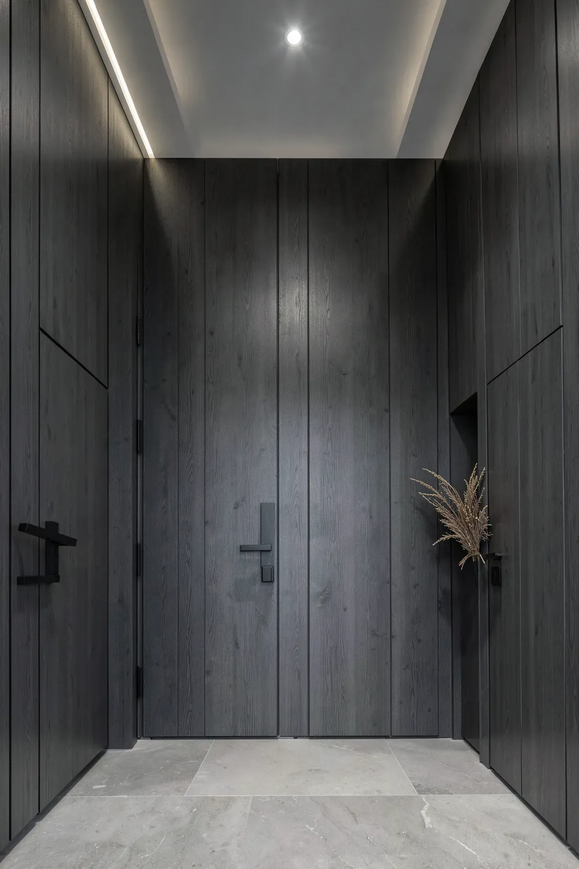 A large entrance hall with dramatic dark charcoal vertical wood paneling and stone floors.