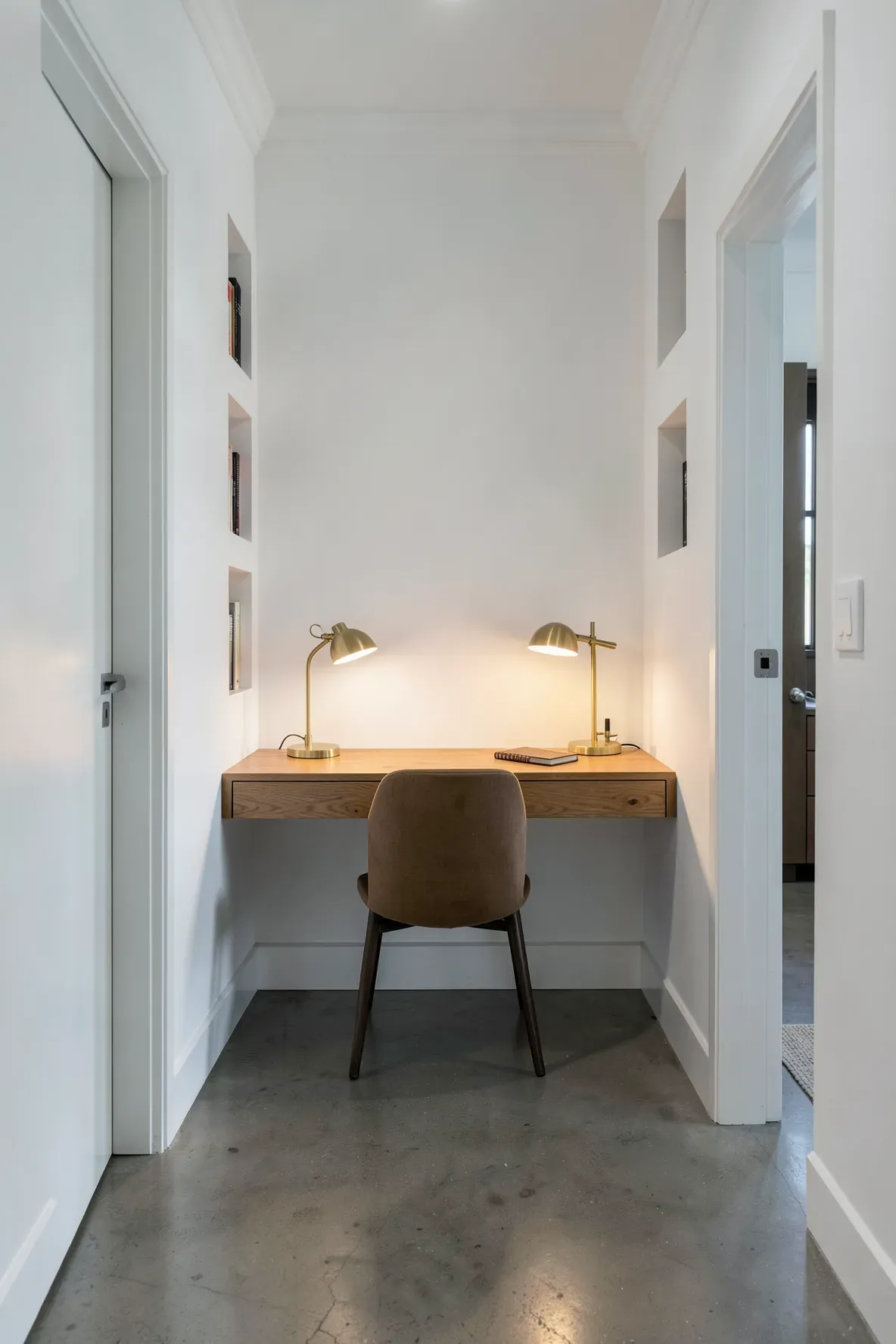 A small floating wooden desk and chair neatly tucked into a wide hallway alcove.