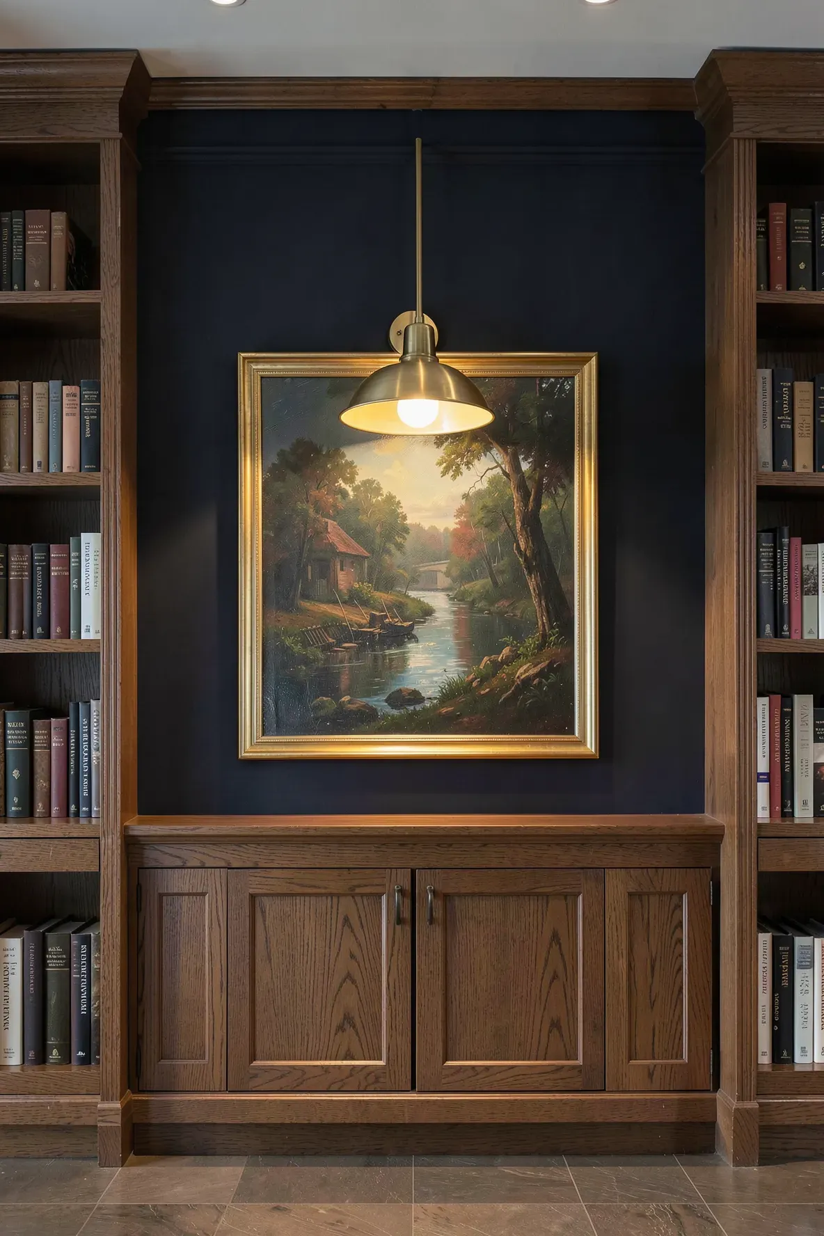A muted gold adjustable picture light illuminating a painting on a dark library wall.