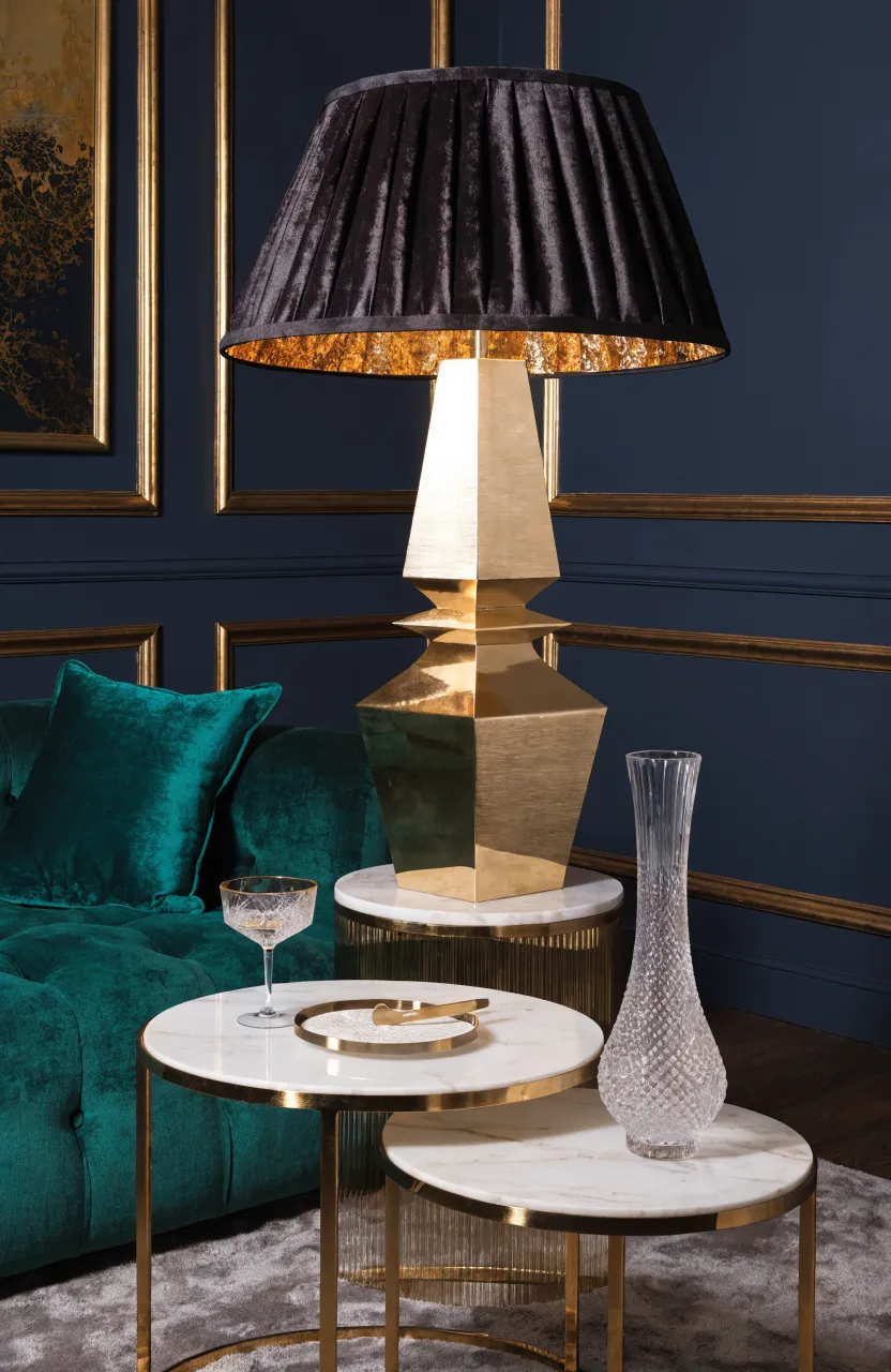 A brushed gold Art Deco lamp with a black shade in a glamorous emerald and navy living room.