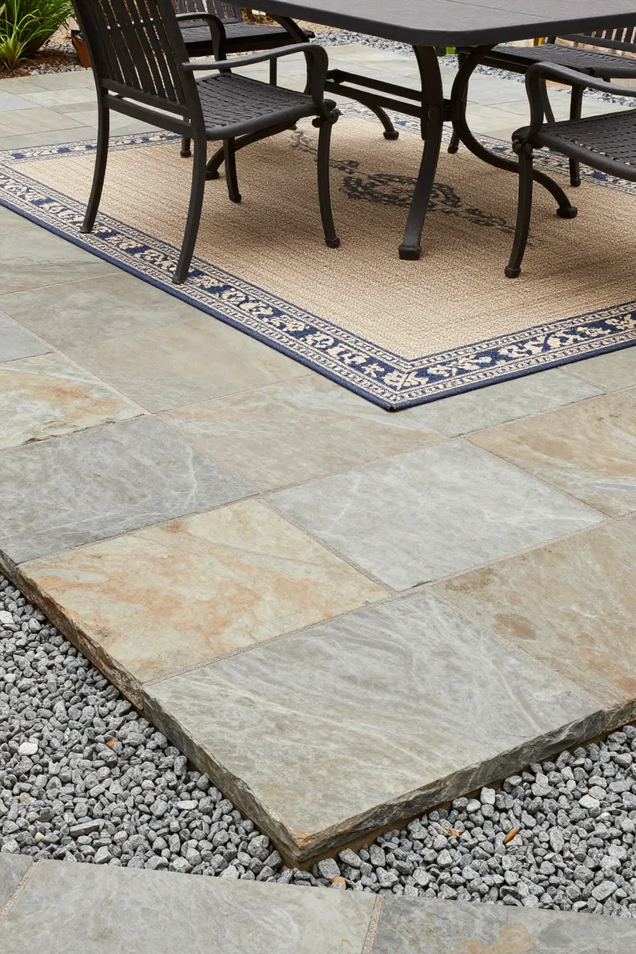 A stone paver patio with a geometric outdoor rug under a dining table.